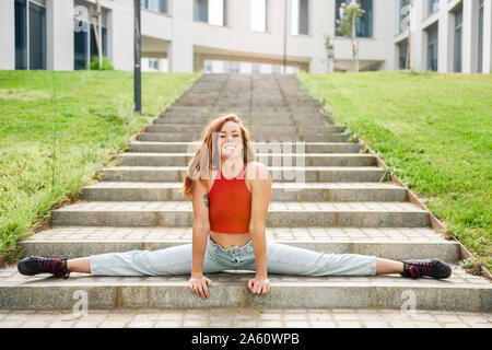 Young woman doing the splits on outdoor stairs Stock Photo