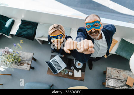 Businessman and woman wearing super hero masks, raising fists Stock Photo