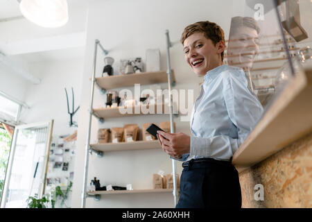 Portrait of happy businesswoman with cell phone in a cafe Stock Photo