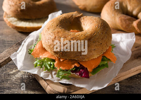 Bagel sandwich with cream cheese, smoked salmon and vegetables on wooden table Stock Photo