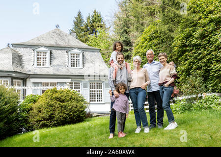 Happy extended family standing in garden of their home Stock Photo