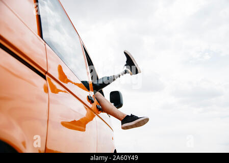 Legs of prosthetic young man dangling out of camper van window Stock Photo