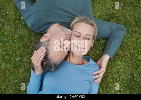 Top view of affectionate mature couple lying in grass Stock Photo