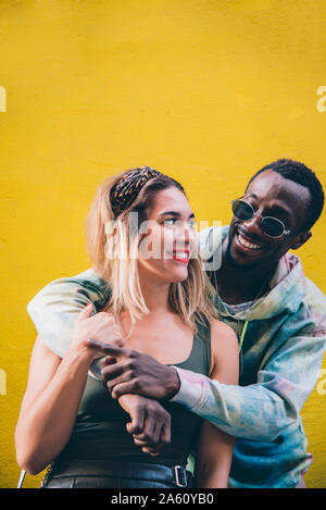 Portrait of happy couple in front of yellow wall Stock Photo