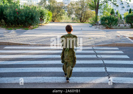 Rear view of a boy wearing a space suit, crossing road, zebra crossing Stock Photo