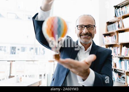 Happy businessman holding toy hot-air balloon Stock Photo