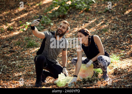 Couple taking a selfie during plogging in forest Stock Photo