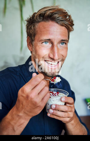 Portrait of smiling young man eating muesli Stock Photo