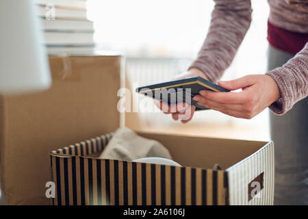 Close-up of woman unpacking cardboard box in new home Stock Photo