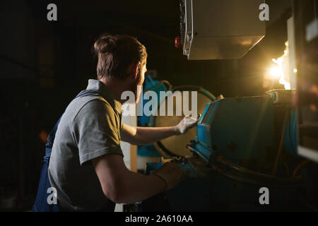 Manual worker in work wear working at the lathe at manufacturing fabric Stock Photo