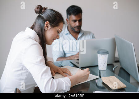 Colleagues with laptop and papers working at table in office Stock Photo