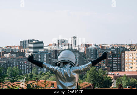 Rear view of boy dressed with raised arms as an astronaut in the city Stock Photo