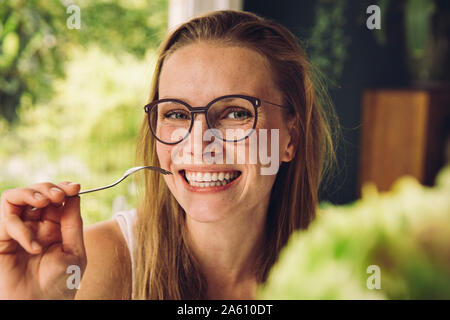 Portrait of happy young woman with glasses holding a fork Stock Photo