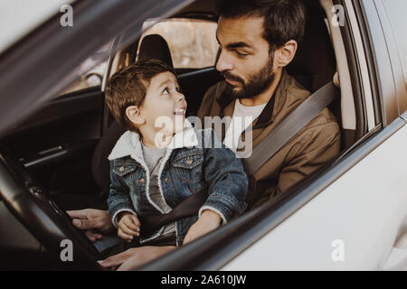 Happy father playing with son in drivers seat in his car. Stock Photo