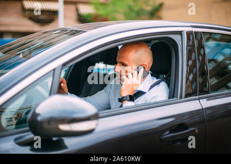 Businessman driving vehicle and using smartphone Stock Photo