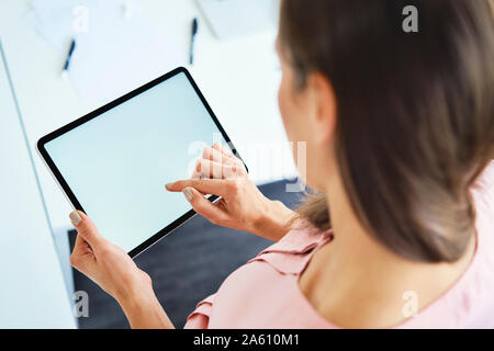 Overhead view of woman using tablet in office Stock Photo