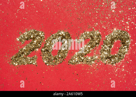 Abstract composition. Christmas, New 2020 year in golden glitter on red background with scattered sparkles Stock Photo