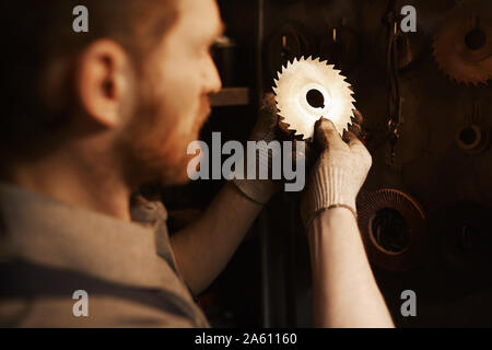 Rear view of young manual worker working with metal details in the factory Stock Photo