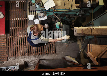 High angle view of manual worker in overalls working on machine in the factory Stock Photo