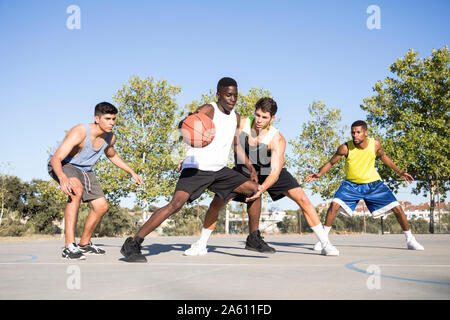 Young men playing basketball and dribbling ball on sports ground Stock Photo