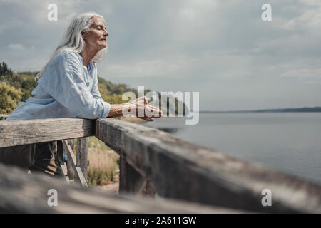 Senior woman standing on bridge, relaxing with eyes closed Stock Photo
