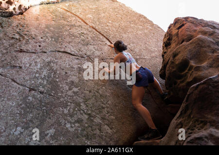 Young Asian woman climbing in a rock wall Stock Photo