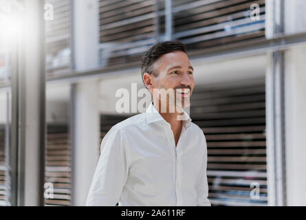 Smiling businessman at a car park wearing white shirt Stock Photo