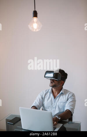 Businessman sitting at table testing VR simulator Stock Photo