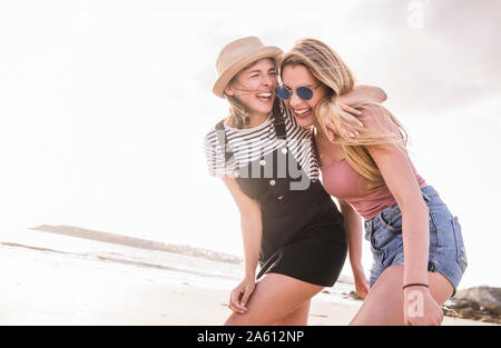 Two girlfriends having fun, walking on the beach Stock Photo