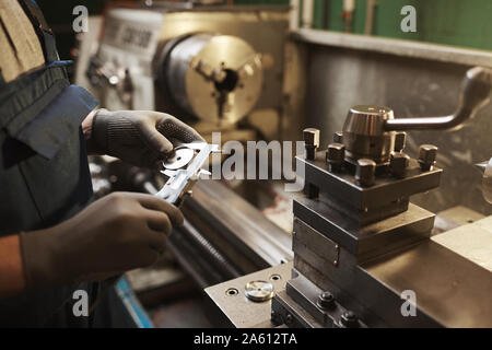 Close-up of manual worker in protective gloves measuring metal detail with special equipment Stock Photo