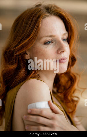 Portrait of redheaded woman with band-aid on her shoulder Stock Photo