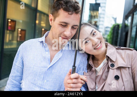 Portrait of happy couple with umbrella in Ginza, Tokyo, Japan Stock Photo