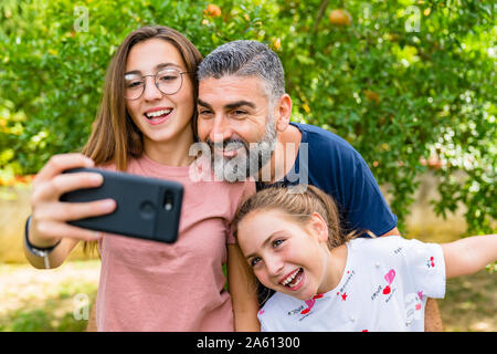 Happy father with two daughters taking selfie in garden Stock Photo
