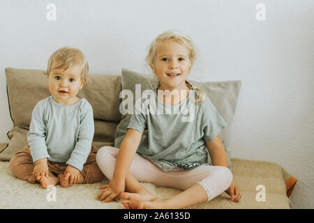 Two sisters sitting side by side at home Stock Photo