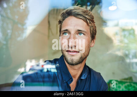 Portrait of young man behind windowpane Stock Photo