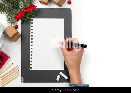 Christmas letter writing on paper on white desk with decorations. Wish list writing. 2020 resolution list Stock Photo
