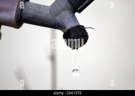 Black plastic faucet dripping water in the garden of residence. Wasting water. With water leak Stock Photo