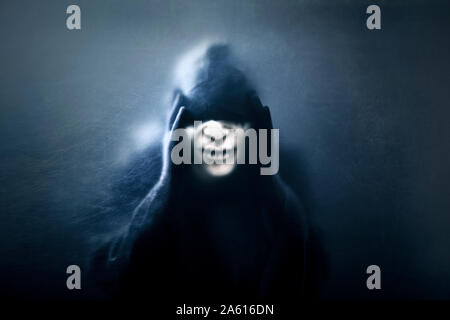 Ghostly figure behind a dusty scratched glass. Scary figure with mask in hooded cloak Stock Photo