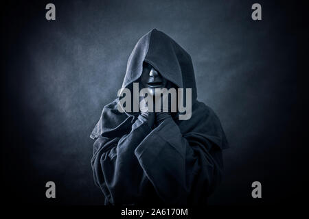 Scary figure with black mask in hooded cloak Stock Photo - Alamy