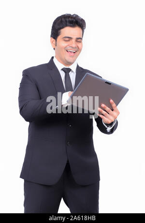 Handsome young businessman using digital tablet. Male professional is preparing presentation on wireless computer. He is wearing formals on white back Stock Photo