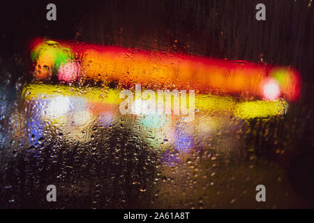 abstract out of focus bold coloured lights shot on the street rain on a car window, high quality good for backgrounds and eye catching advertising. Stock Photo