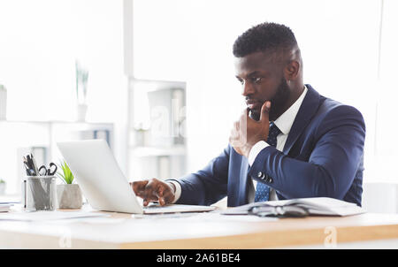 Thoughtful young manager making research online, using laptop Stock Photo