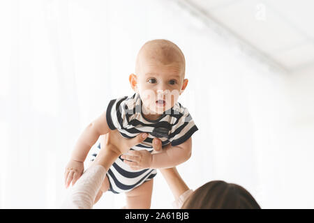Unrecognizable woman lifting cute little baby in the air Stock Photo