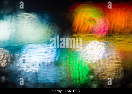 abstract out of focus bold coloured lights shot on the street rain on a car window, high quality good for backgrounds and eye catching advertising. Stock Photo