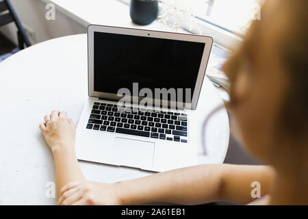 Blurried woman working with laptop, focus on computer. Stock Photo