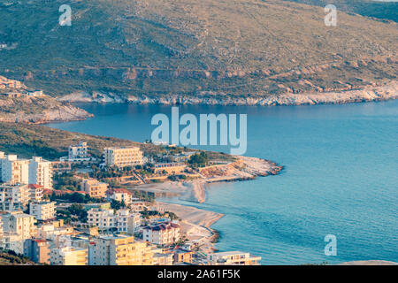 Golden hour landscape and cityscape from Lekuresi Castle, Saranda, Albania with Adriatic Sea coast and residential district view, clear spring sky with evening haze Stock Photo