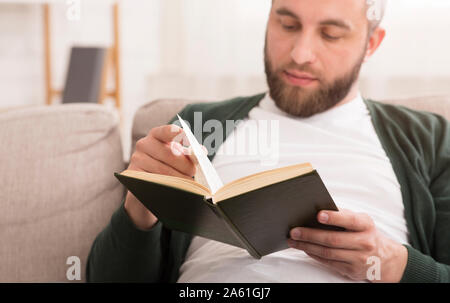 Close up of bearded man reading book at home Stock Photo