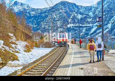 HALLSTATT, AUSTRIA - FEBRUARY 21, 2019: The modern train arrives to Hallstatt Bahnhof railway station, located at the foot of Sarstein mount on the ba Stock Photo