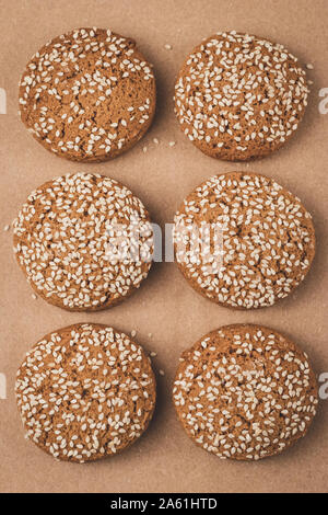 Oat cookie with sesame seeds on craft paper. Brown background. Homemade baking. Stock Photo