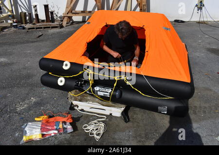 Man inside inflated life raft on land Stock Photo